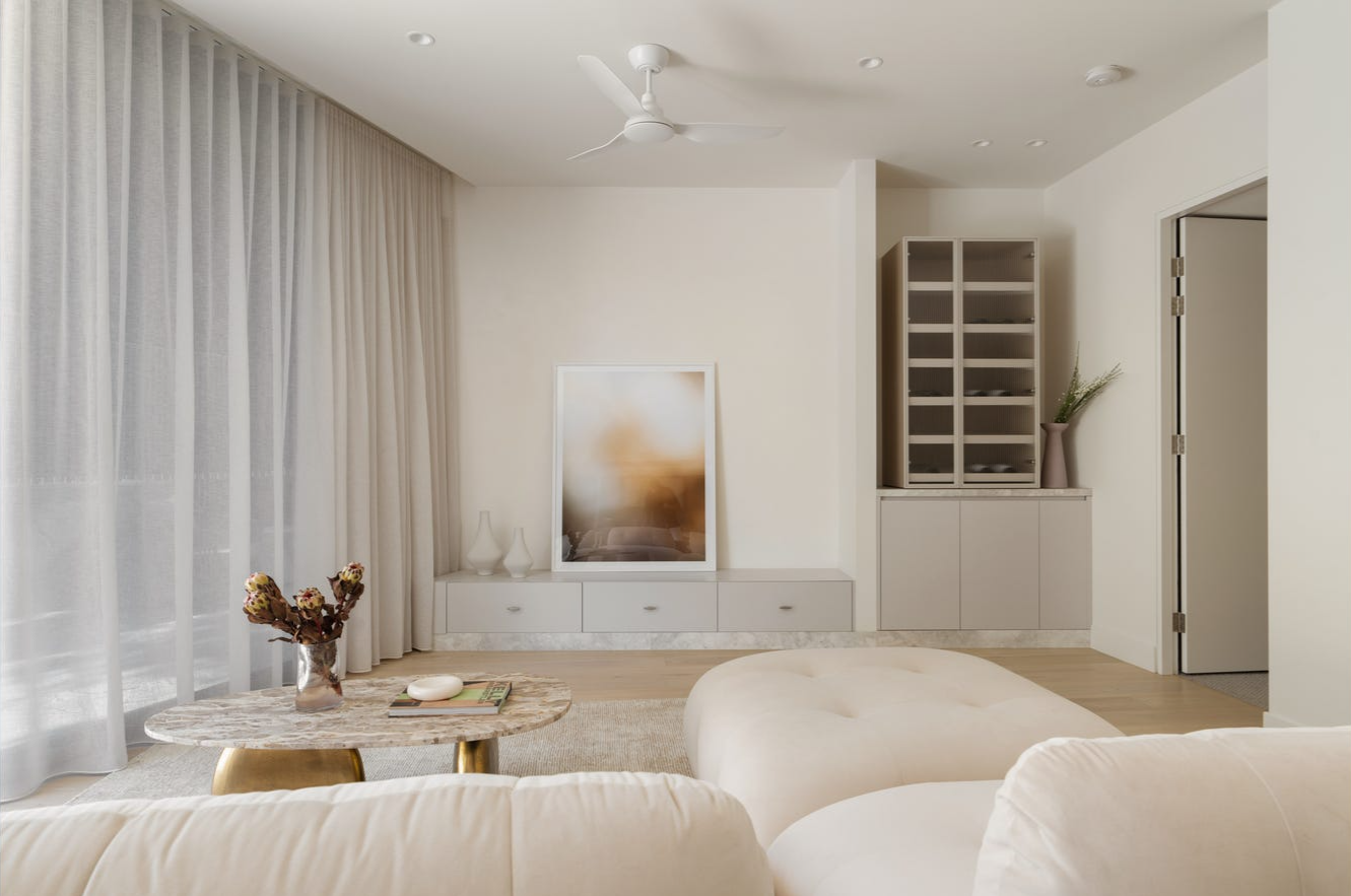 Modern Living Room from a Gold Coast interior designer and stylist that includes a neutral modular sofa, neutral rug, brown vein marble coffee table with brass legs and abstract art that sits a top a white entertainment unit. 